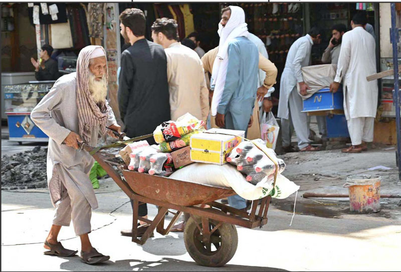 پشاور،ایک ضعیف شخص اپنا اور اپنے خاندان والوں کا پیٹ پالنے کے لیے سامان سے بھری ٹرالی لے جارہا ہے
